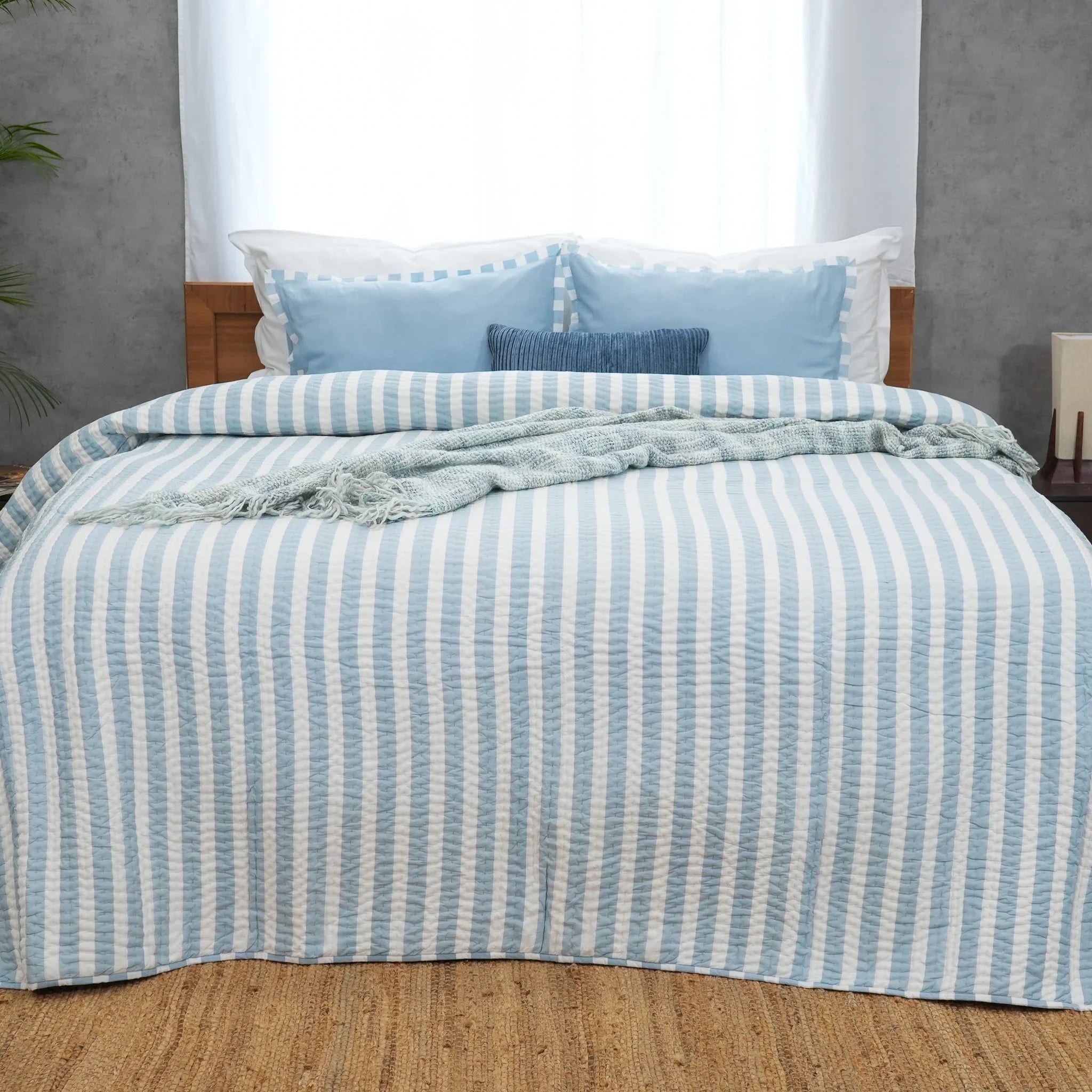 Blue and white striped cotton quilt on a neatly made bed