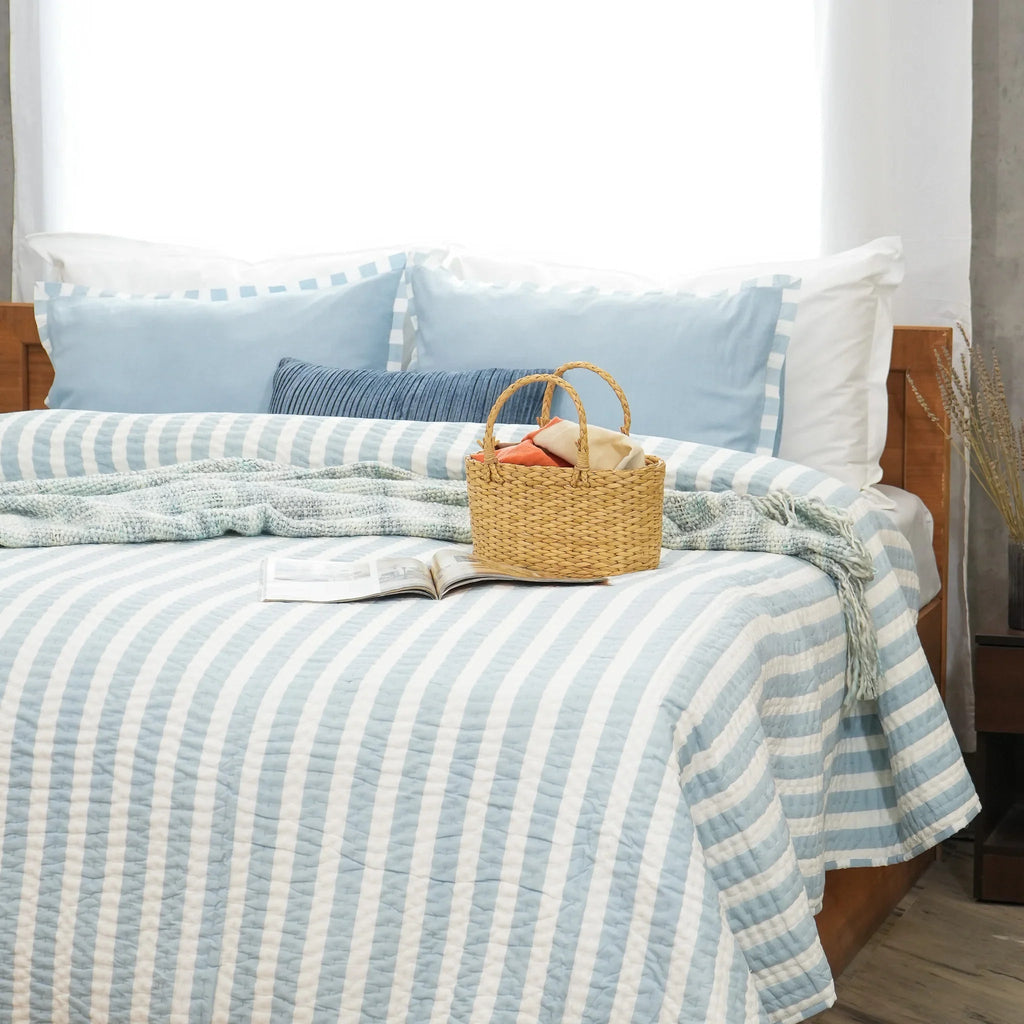 Blue and white striped cotton quilt styled with decorative breakfast tray