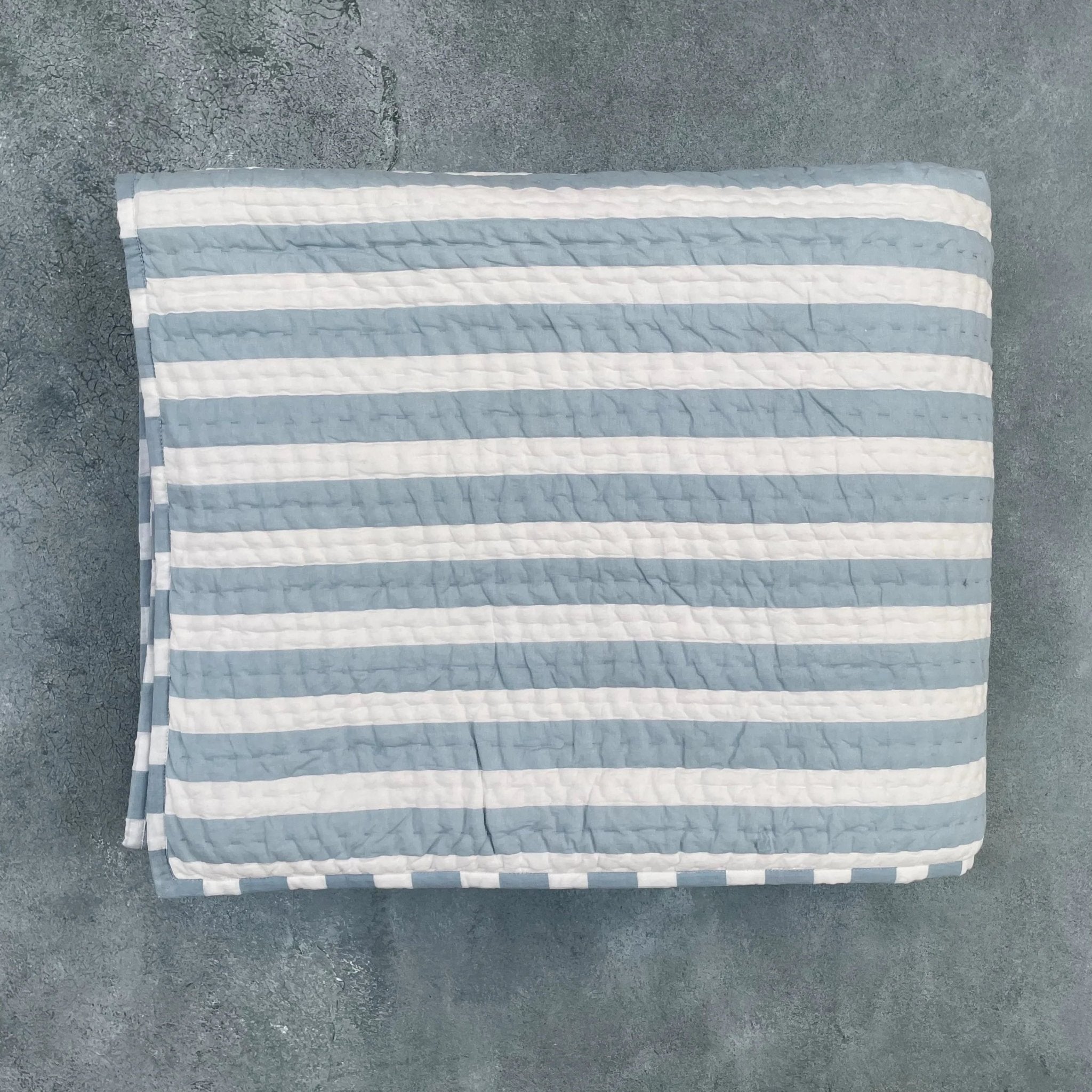 Flat lay of blue and white striped cotton quilt