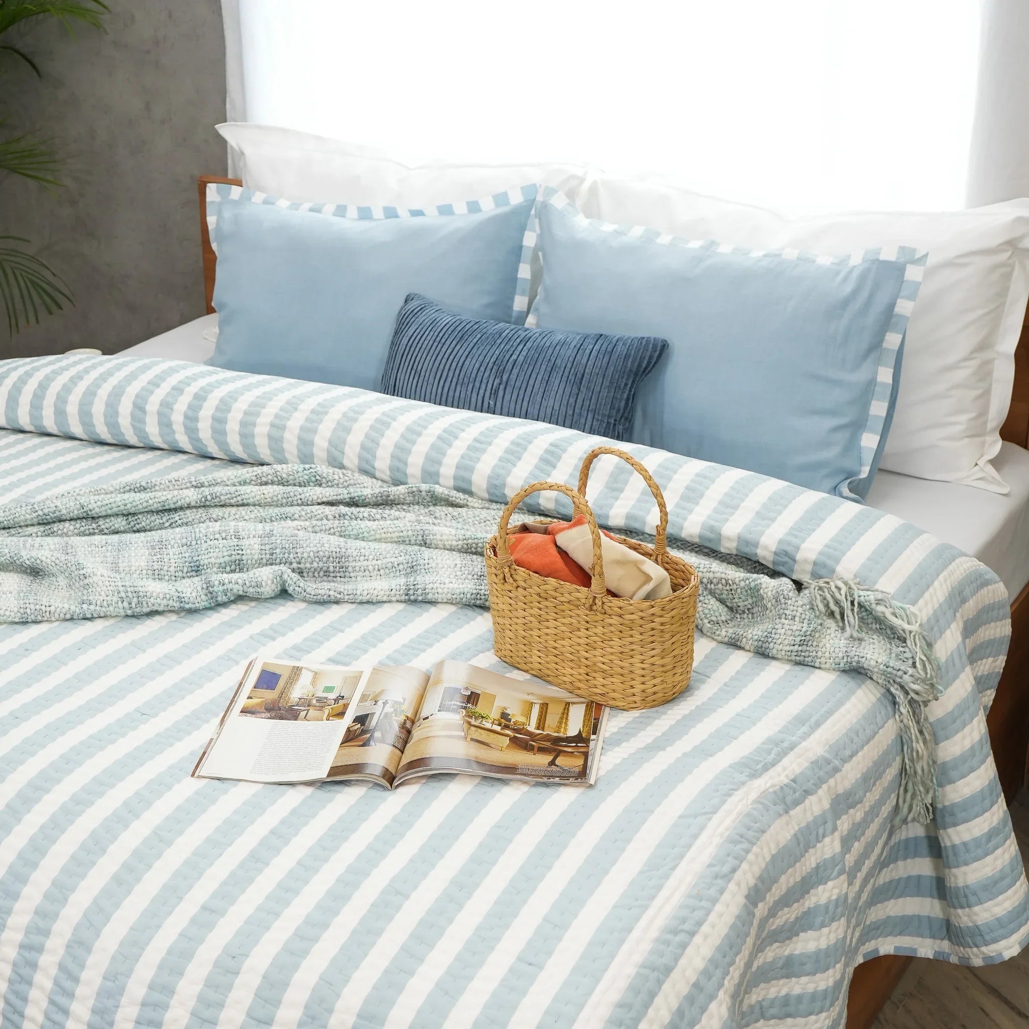 Blue and white striped cotton quilt styled with magazine on bed