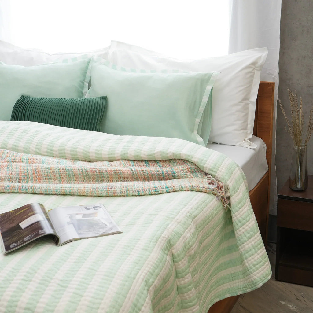 Green and white striped cotton quilt styled in a bright modern bedroom