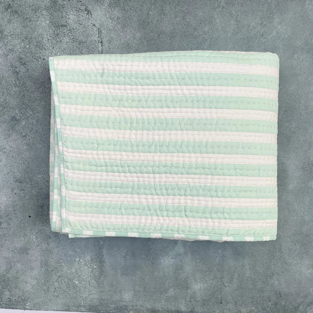 Flat lay of green and white striped cotton quilt