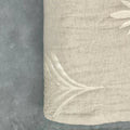 Close-up of natural embroidered cotton-linen quilt with palm embroidered detail