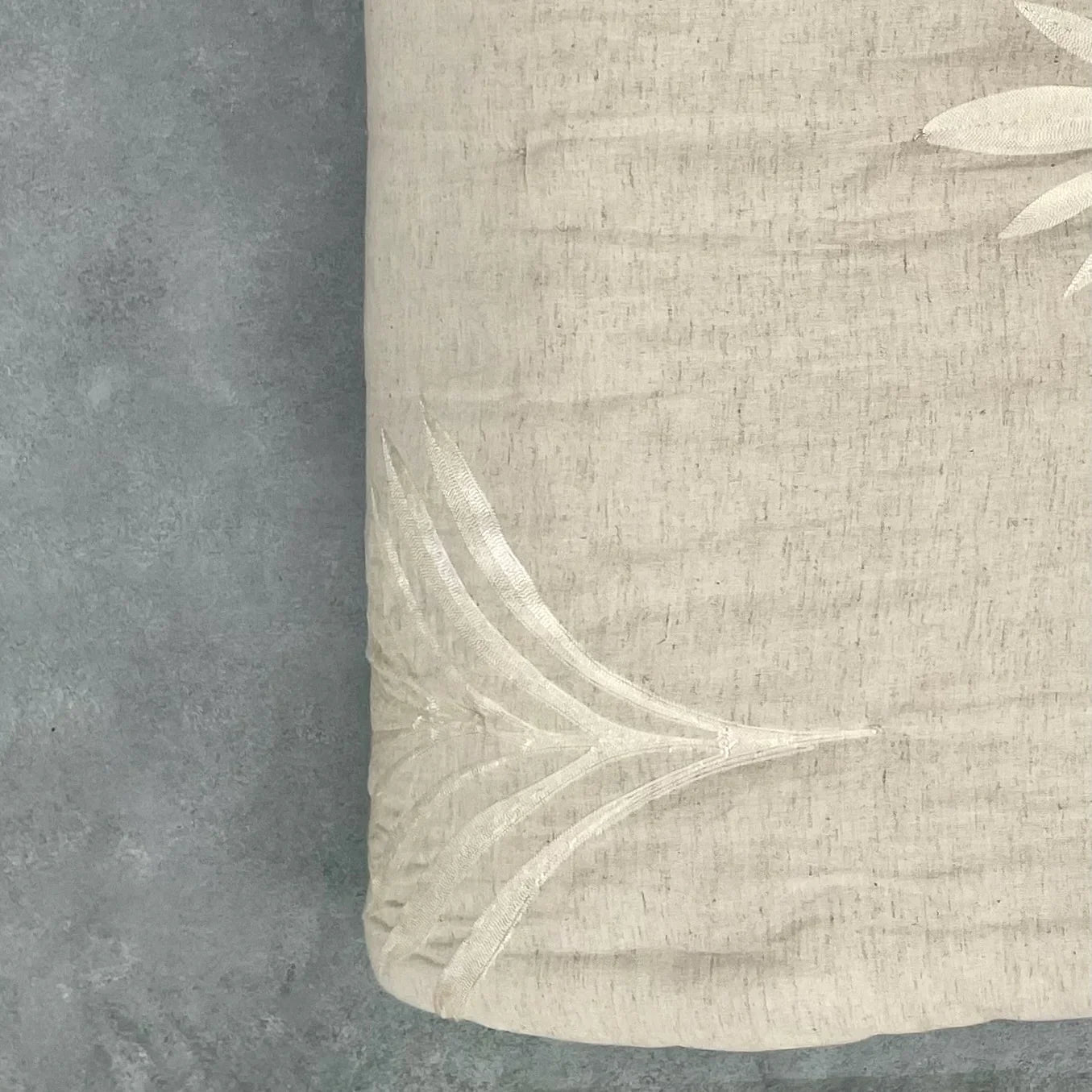 Close-up of natural embroidered cotton-linen quilt with palm embroidered detail