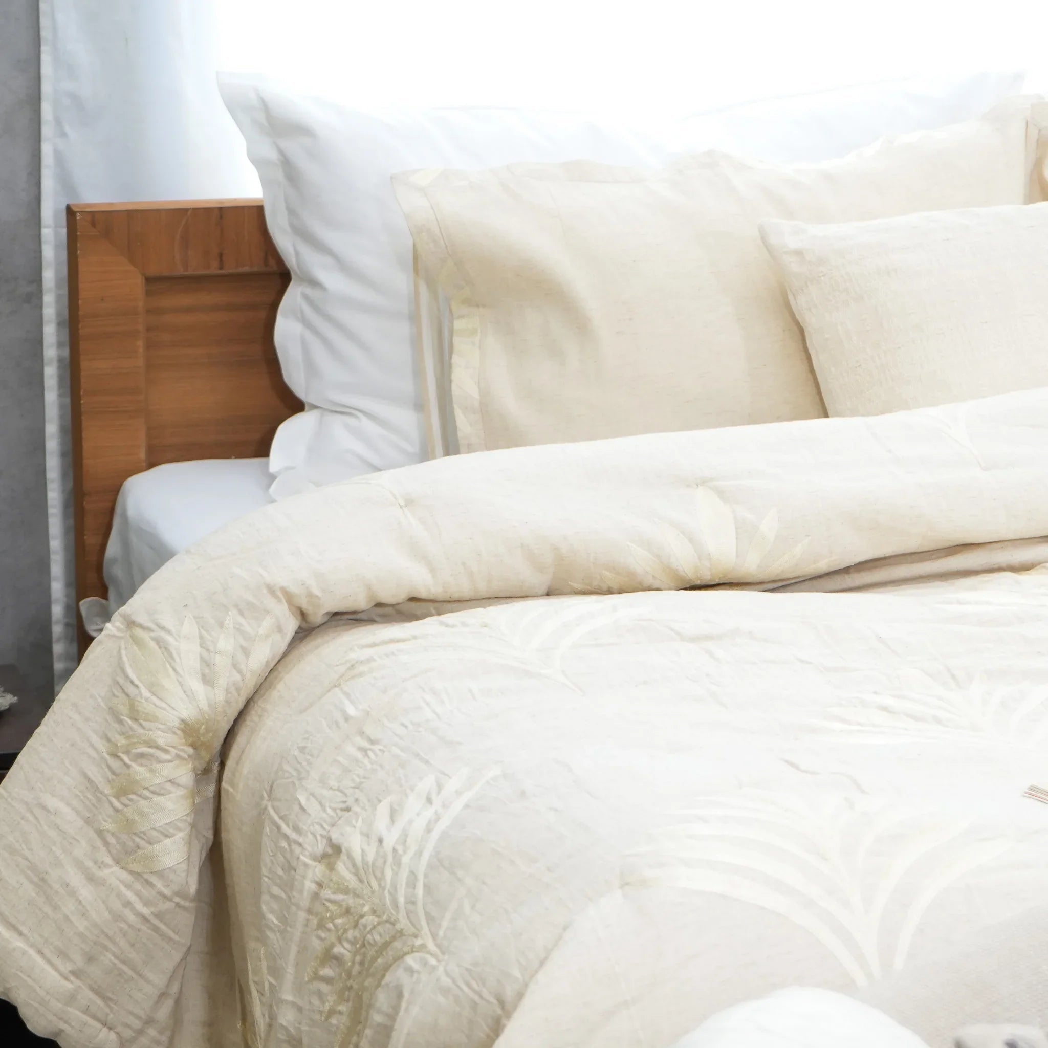 Natural embroidered cotton-linen quilt styled on a bed with matching pillows
