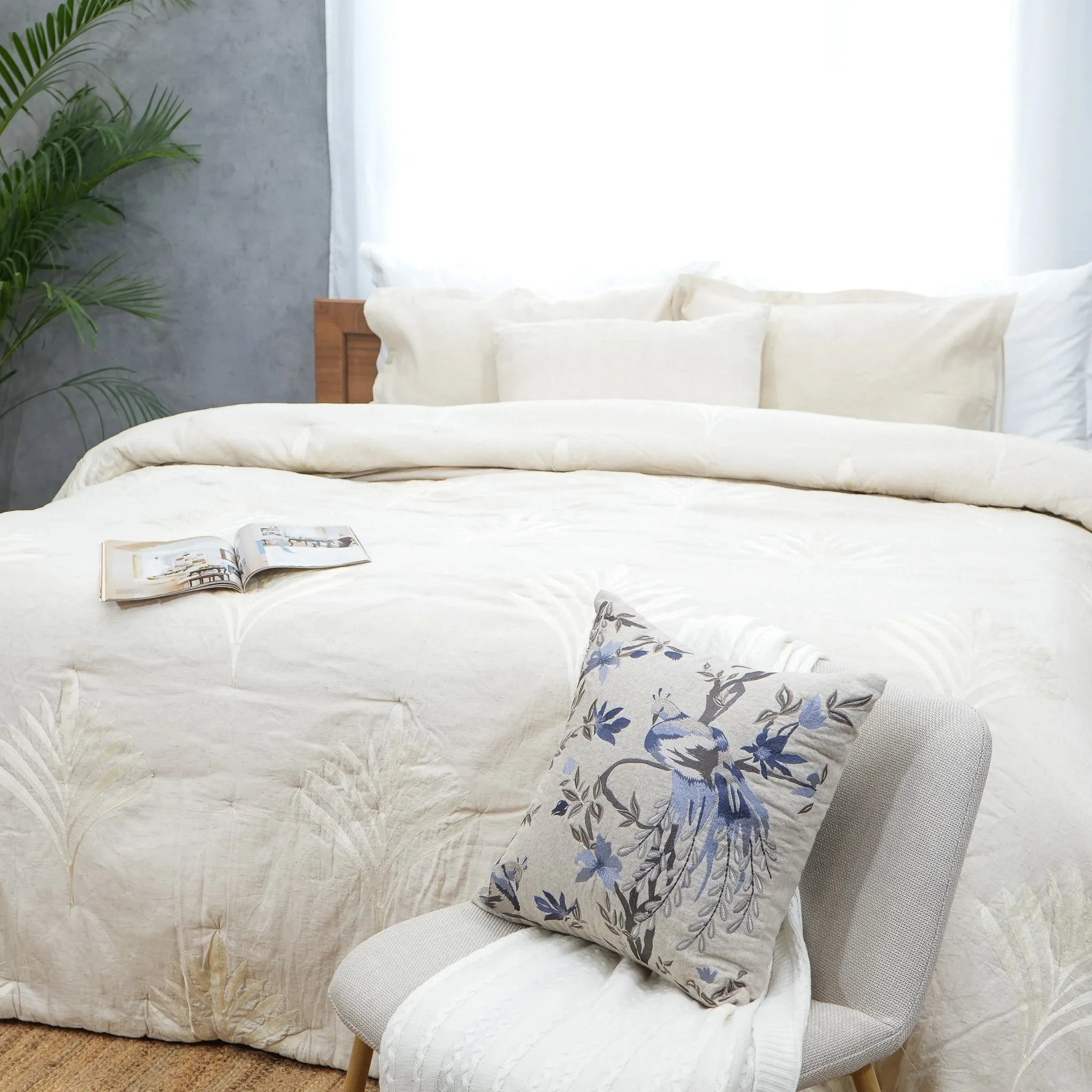 Wide view of natural embroidered cotton-linen quilt with coordinating cushion