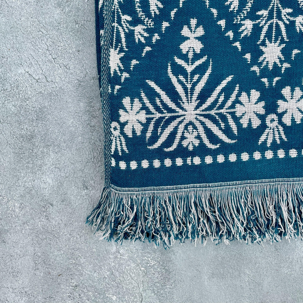 Folded blue jacquard floral throw highlighting fringe and floral border