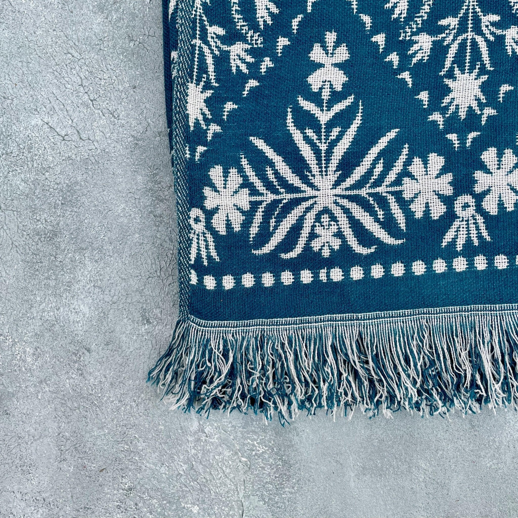 Folded blue jacquard floral throw highlighting fringe and floral border