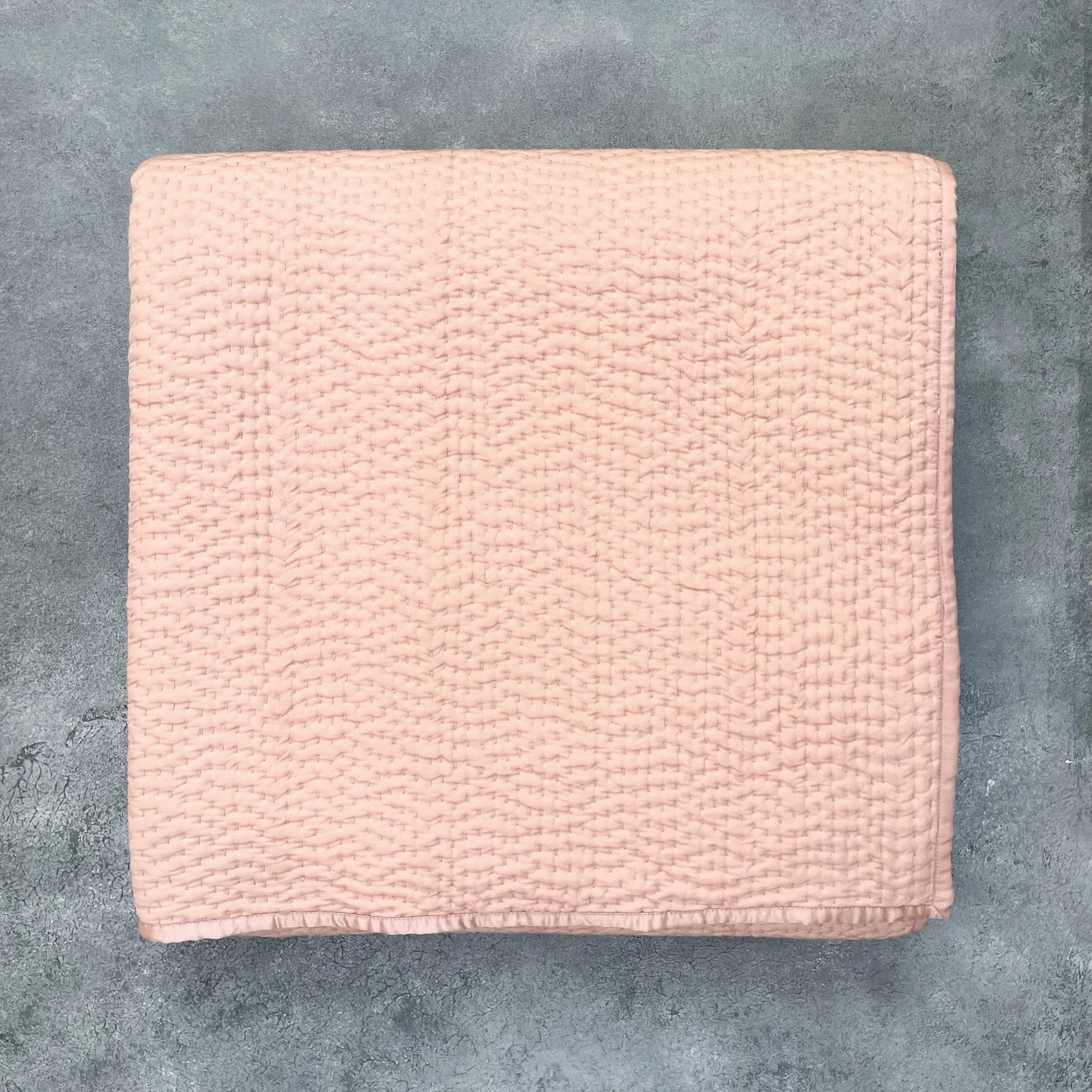 Flat lay of Rose Gold Kantha silk quilt showing hand quilted texture