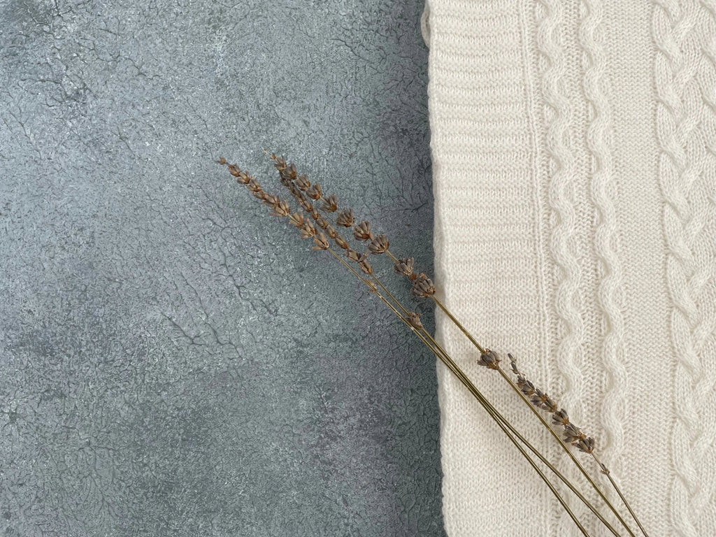 Corner detail of ivory cotton cable knit throw with cable knit pattern and flowers