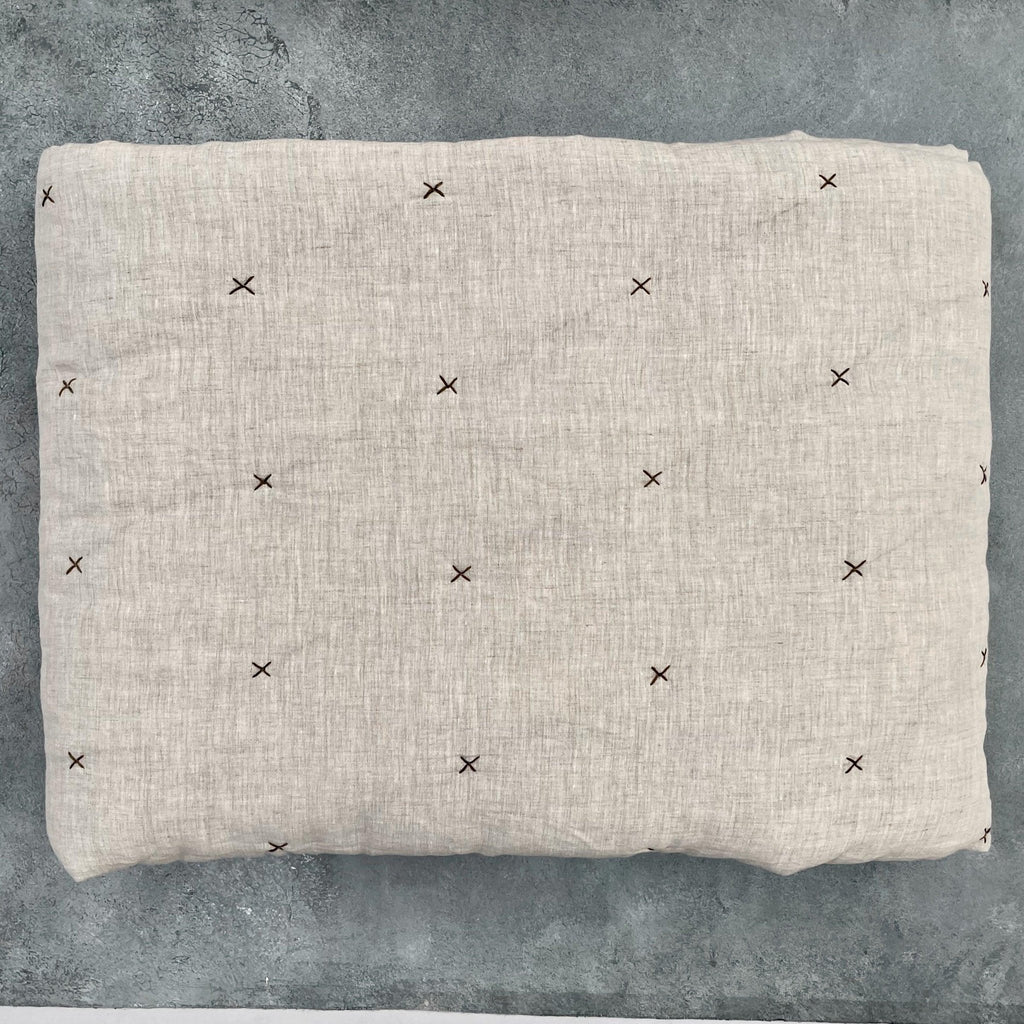 Flat lay of natural ivory chambray pure linen quilt showing star quilting