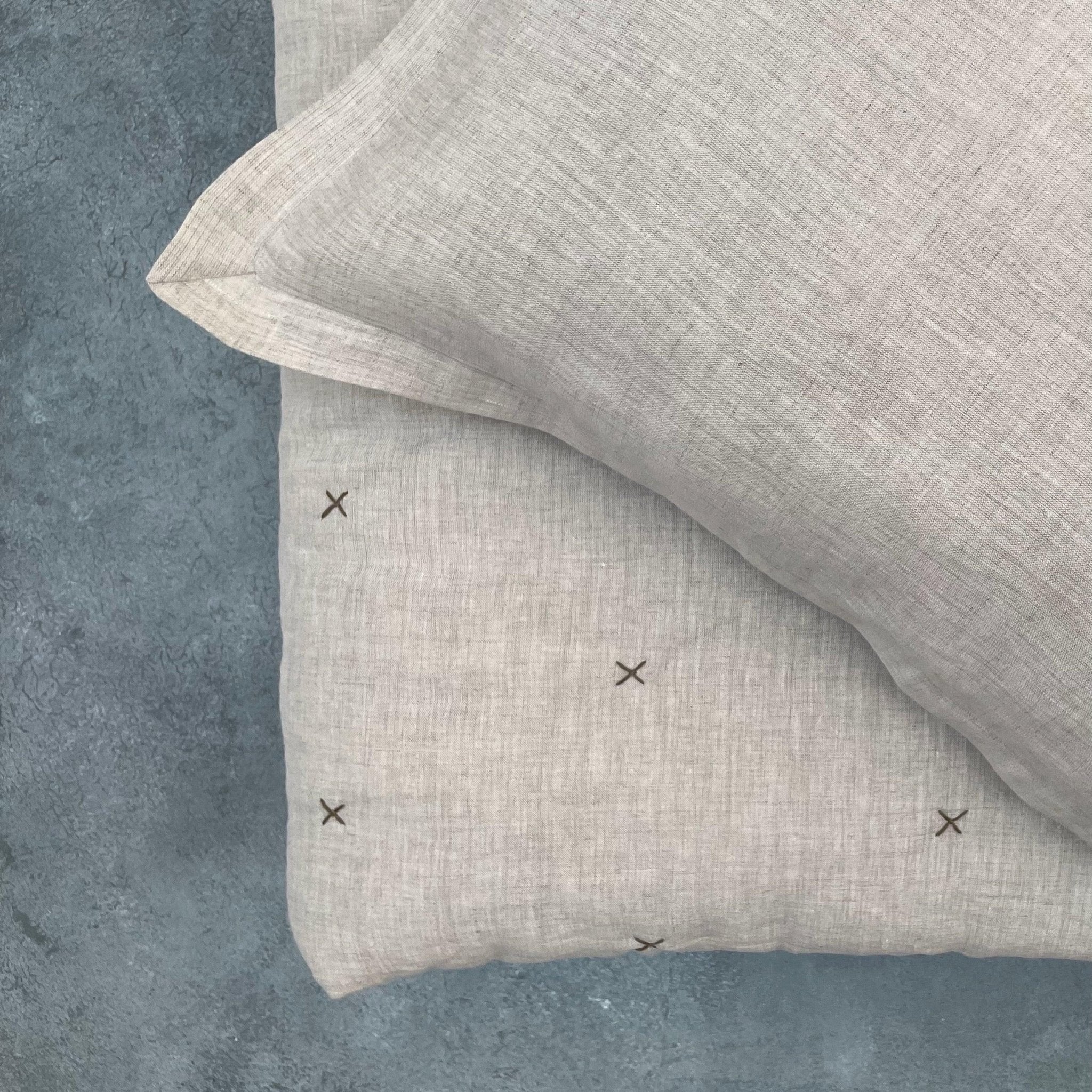 Folded natural ivory chambray pure linen quilt showing stitched detailing