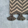 Close-up of grey and beige acrylic crochet throw with chevron weave and tassels