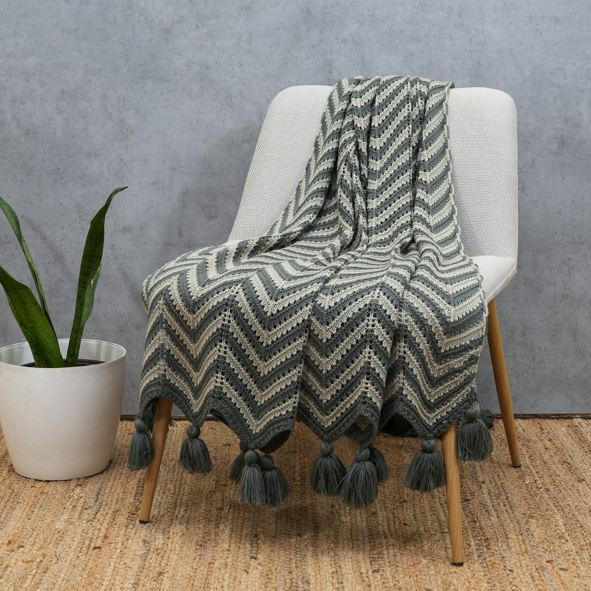 Grey and beige crochet acrylic throw draped over a wooden accent chair