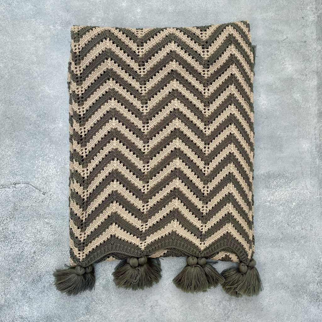 Flat lay of grey and beige crochet acrylic throw on grey textured background