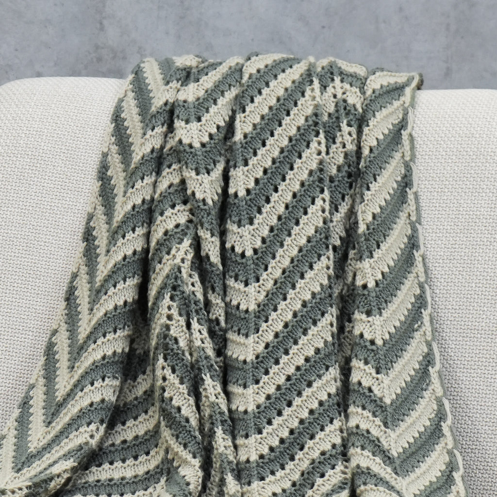 Close-up of grey and beige crochet acrylic throw with chevron pattern