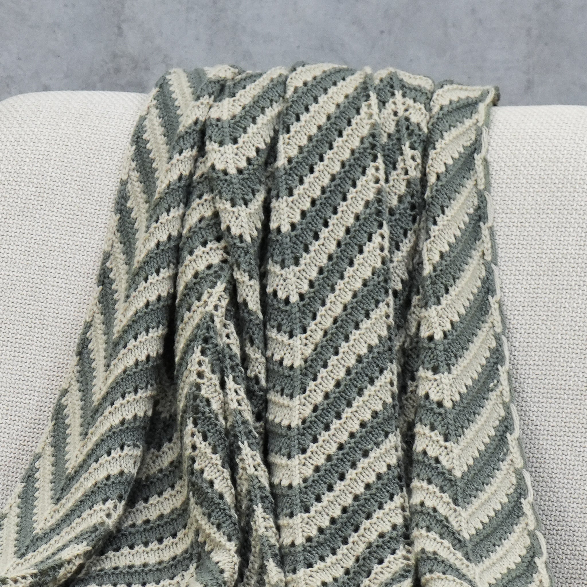 Close-up of grey and beige crochet acrylic throw with chevron pattern